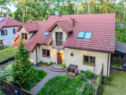 Józefów, dom wolnostojący otoczony sosnami.