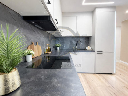 Wiesia w fartuchu w kratę stoi z wałkiem w ręku.