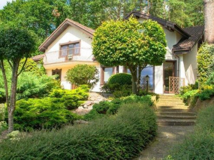 Dom pod maistem zatopiony w zieleni.